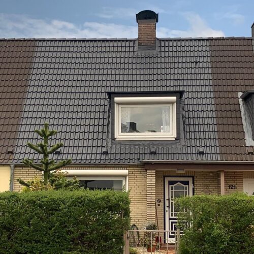 Dach eines Reihenhauses. Mittelhaus nach Dachreinigung und Dachversiegelung im Vergleich mit nicht gereinigten Häusern links und rechts