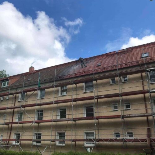 Dachreiniger auf dem Dach eines Mehrfamilienhauses bei der Dachrenigung